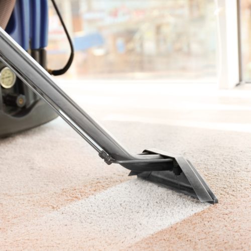 Cleaning service concept. Steam vapor cleaner removing dirt from carpet in flat, closeup