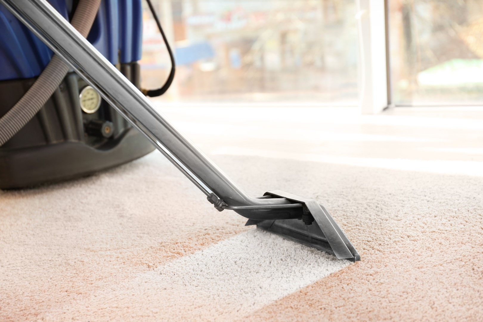 Cleaning service concept. Steam vapor cleaner removing dirt from carpet in flat, closeup